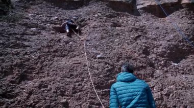 Arkadaşlar doğada kırmızı kayalara tırmanıyor. Yüksek kalite 4k görüntü