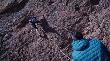 Arkadaşlar doğada kırmızı kayalara tırmanıyor. Yüksek kalite 4k görüntü