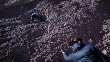 Arkadaşlar doğada kırmızı kayalara tırmanıyor. Yüksek kalite 4k görüntü