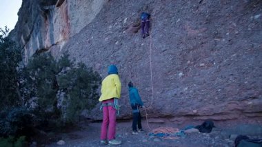 Arkadaşlar doğada kırmızı kayalara tırmanıyor. Yüksek kalite 4k görüntü