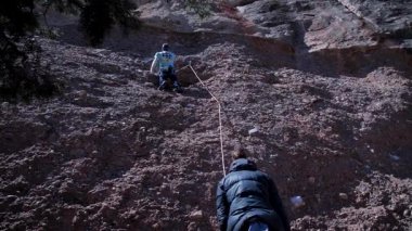 Arkadaşlar doğada kırmızı kayalara tırmanıyor. Yüksek kalite 4k görüntü