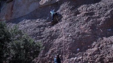Arkadaşlar doğada kırmızı kayalara tırmanıyor. Yüksek kalite 4k görüntü