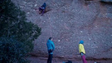 Arkadaşlar doğada kırmızı kayalara tırmanıyor. Yüksek kalite 4k görüntü