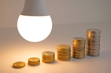 Yanında bozuk paralar olan bir ampul. Enerji tarifelerini arttırın. Verimlilik ve enerji tasarrufu. 