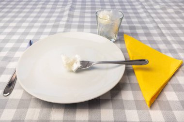 Beyaz tabaklar ve plastik atık içeren camlarla döşenmiş bir masa. Çevrede plastik, yiyecekte mikro plastik.. 