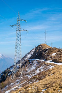 Elektrik direkleri, bir dağ yerinde. Köken, ulaşım ve elektrik ihtiyacı. Çevresel tahribat. Elektirik ızgarası.
