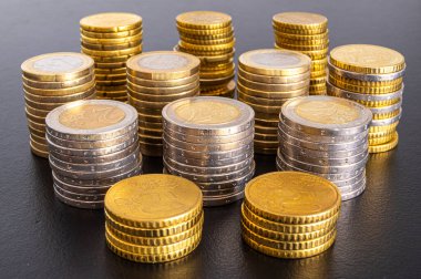 Siyah yüzeyde, para yığınları yan yana. Para ve zenginlik miktarı. 