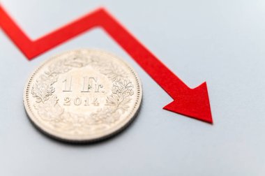 1 İsviçre Frangı sikkesi, aşağı inen çizginin yanında. İsviçre Frangı 'nın değeri ve düşen döviz kuru.