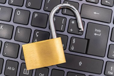 Bilgisayar klavyesinin üzerine yerleştirilmiş asma kilidi aç. Kişisel ve hassas verilerin korunması, izinsiz girme riski. Mahremiyet.