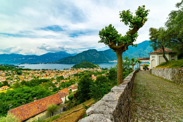 stock image The panorama of Lake Como photographed from the town of Colonno, showing the town of Colonno, a stretch of cobbled road, and the panorama of the lake.