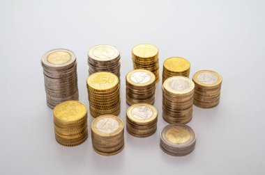 Beyaz yüzeyde, para yığınları yan yana. Paranın miktarı, para birimi ve zenginlik.