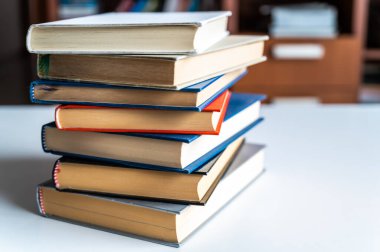 Beyaz yüzeyde, yakından fotoğraflanmış bir yığın kitap..