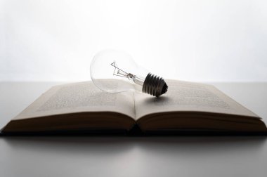 Açık kitap, arka plan, üstünde ampul var. Fikir, çalışma, yaratıcılık ve yenilik.