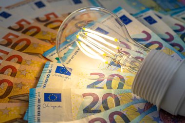 Avro banknotlarının üstünde bir ampul yandı. Elektrik maliyeti ve tarifeleri.