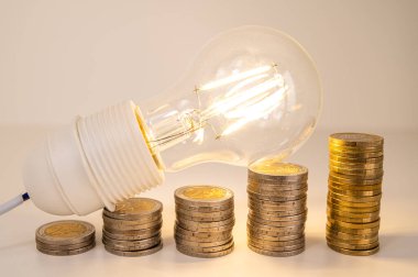 Ampul yandı, bozuk para yığınlarının üstünde. Elektrik tarifelerinde artış, enerji bağımlılığı, enerji arzında artış.