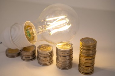 Ampul yandı, bozuk para yığınlarının üstünde. Elektrik tarifelerinde artış, enerji bağımlılığı, enerji arzında artış.