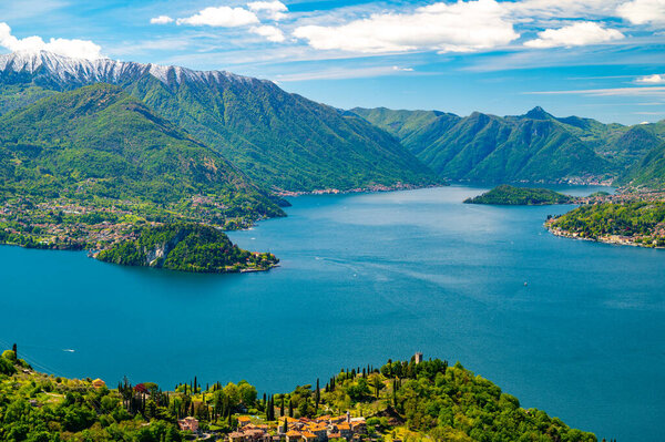 Lake Como, seen from Perledo, with Varenna, Bellagio, Vezio Castle, Punta Balbianello, on a spring day, with snow-capped mountains.