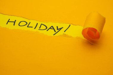 Sarı yüzey, tatili simsiyah, yırtılmış ve yuvarlanmış turuncu kartın altında.