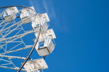 Güneşli bir günde, arka planda mavi gökyüzü ile aşağıdan çekilen dönme dolap..