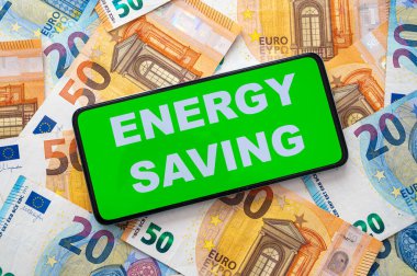 Enerji Tasarruf metni olan aygıt, banknot arka planında. Enerji tasarrufu ve para tasarrufu.