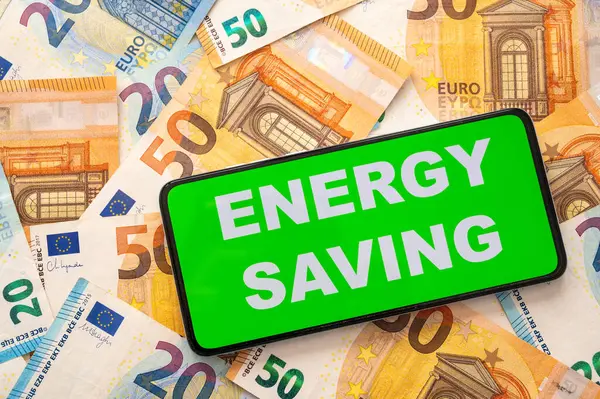 Enerji Tasarruf metni olan aygıt, banknot arka planında. Enerji tasarrufu ve para tasarrufu.