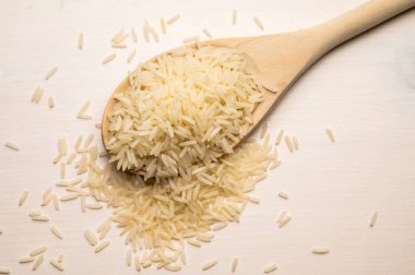 Çiğ basmati pilavı, ahşap kepçe, hafif ahşap yüzey üzerinde.