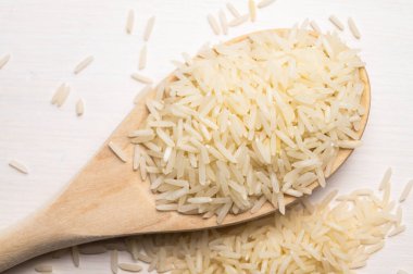 Çiğ basmati pilavı, ahşap kepçe, hafif ahşap yüzey üzerinde.