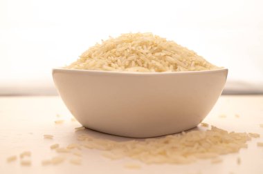 Çiğ basmati pilavı, beyaz kâse içinde, hafif ahşap yüzey üzerinde..