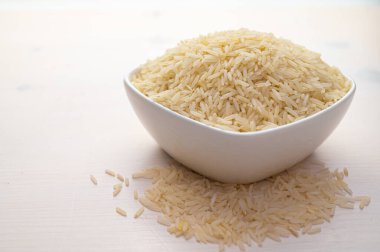 Çiğ basmati pilavı, beyaz kâse içinde, hafif ahşap yüzey üzerinde..