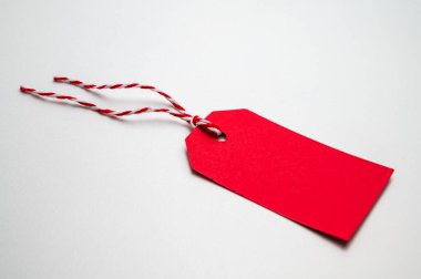 Kırmızı Noel kartı, beyaz arka planda, bağlı bir ip. Noel, hediyeler ve Noel selamları.