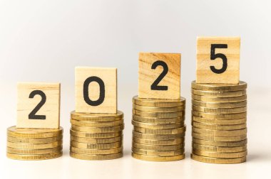 Yığınla bozuk para ve 2025 rakamını heceleyen tahta küpler. Yeni yıl, ekonomi ve zenginlik.