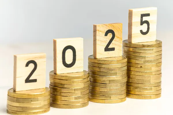 Yığınla bozuk para ve 2025 rakamını heceleyen tahta küpler. Yeni yıl, ekonomi ve zenginlik.