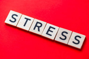 Sözcük stresi, kırmızı yüzeyde tahta alfabe bloklarıyla oluşturulmuş..