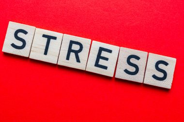 Sözcük stresi, kırmızı yüzeyde tahta alfabe bloklarıyla oluşturulmuş..