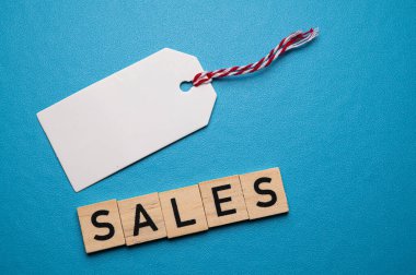 Sözcük satışları, ahşap alfabe bloklarından oluşmuş, ve beyaz ve kırmızı biletlerle, iple, mavi bir yüzeyde. Satışlar ve tanıtım satışları.