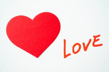 Aşk kelimesi, kırmızı ile yazılmış, kırmızı kalplerin yanında, beyaz bir yüzeye..