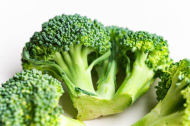 Brokoli, beyaz yüzeye yerleştirilmiş. Besleyici nitelikler ve tarifler.