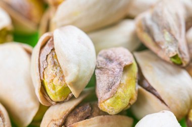 Kabuklu fıstıklar, beyaz kâse, yeşil peçete ve ahşap yüzey. Mülkiyet ve fıstık kullanımı.