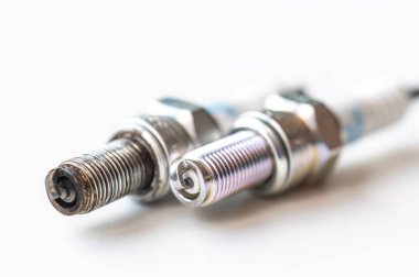 Beyaz yüzeydeki içten yanmalı motor için yeni ve kullanılmış bujiler. Bakım, bakım, motorun verimliliği.