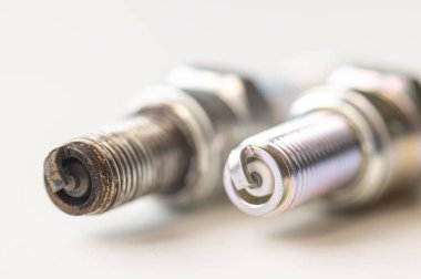 Beyaz yüzeydeki içten yanmalı motor için yeni ve kullanılmış bujiler. Bakım, bakım, motorun verimliliği.