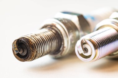Beyaz yüzeydeki içten yanmalı motor için yeni ve kullanılmış bujiler. Bakım, bakım, motorun verimliliği.