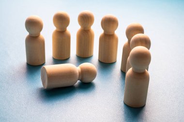 İş yerinde mafya, dışlanma ve psikolojik şiddet kavramı. Ahşap piyonlarla soyut bir tasvir, diğer insanlar tarafından hedef alınan bir kişinin..