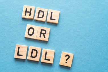 HDL ve LDL kolesterol arasındaki fark kavramı, mavi arkaplandaki ahşap alfabeyle oluşmuş terimlerle; kötü kolesterol LDL.