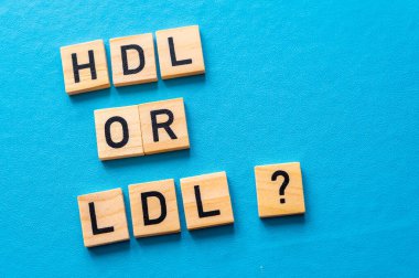 HDL ve LDL kolesterol arasındaki fark kavramı, mavi arkaplandaki ahşap alfabeyle oluşmuş terimlerle; kötü kolesterol LDL.