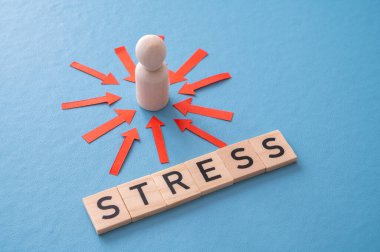 Stres konsepti ve stresli insan. Üzerinde kırmızı oklar olan ahşap bir figür ve ahşap alfabeyle oluşturulan stres sözcüğü..