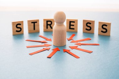 Stres konsepti ve stresli insan. Üzerinde kırmızı oklar olan ahşap bir figür ve ahşap alfabeyle oluşturulan stres sözcüğü..