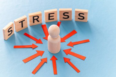 Stres konsepti ve stresli insan. Üzerinde kırmızı oklar olan ahşap bir figür ve ahşap alfabeyle oluşturulan stres sözcüğü..