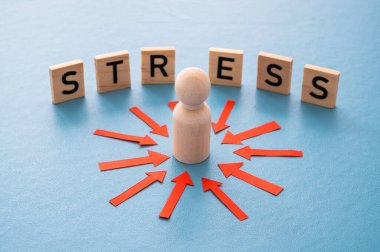 Stres konsepti ve stresli insan. Üzerinde kırmızı oklar olan ahşap bir figür ve ahşap alfabeyle oluşturulan stres sözcüğü..