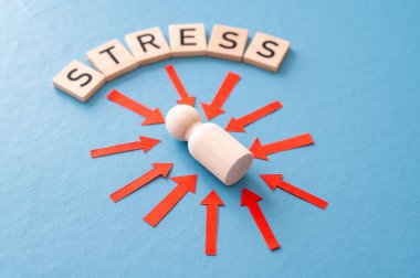 Stres konsepti ve stresli insan. Üzerinde kırmızı oklar olan ahşap bir figür ve ahşap alfabeyle oluşturulan stres sözcüğü..