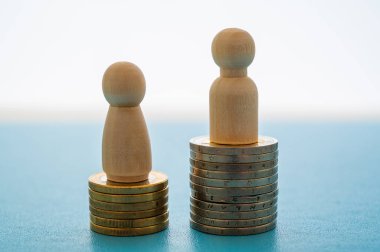 Kadınlar ve erkekler arasındaki iş yerinde eşit ücret kavramı. Bozuk para yığınları üzerinde tahta figürler.